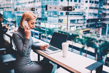 Blonde young woman calling to operator via smartphone to check status of bank account sitting at...