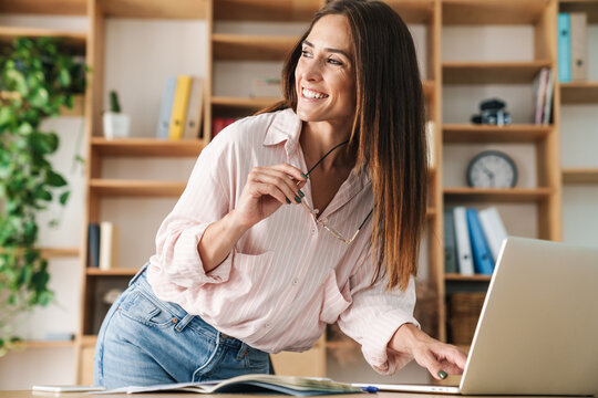 Image of happy adult businesswoman smiling while working with laptop