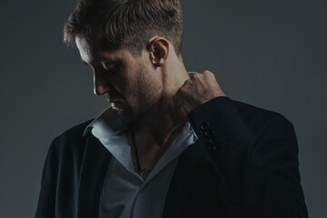 Fototapeta premium Portrait of stylish and sexy young bearded businessman adjusting his collar. Horizontal image.