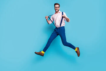 Full length profile photo of handsome business man jump high shopping center running crazy addicted shopaholic wear specs shirt suspenders pants boots isolated blue color background