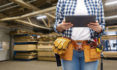industry, production and job concept - close up of woman or worker with tablet pc computer working tools on belt over factory workshop on background