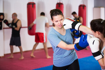 Two young athlete girls practicing boxing sparring at sport class