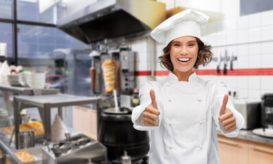 cooking, gesture and people concept - happy smiling female chef in toque showing thumbs up over...