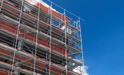 Fototapeta premium architecture and urban concept - multi-storey building under construction with scaffolding