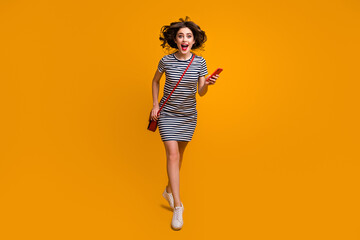 Fototapeta na wymiar Full size photo of funny lady rush shopping center read telephone sale season opening open mouth wear casual striped mini dress clutch shoes isolated yellow color background