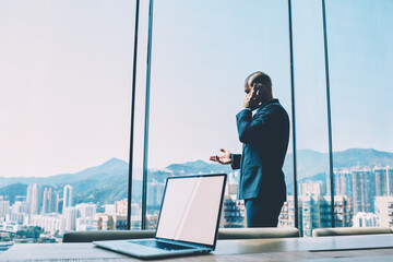 Experienced banker communicating about business project on smartphone standing in modern office...