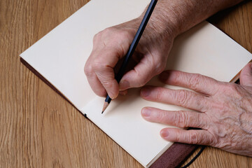 Ederly woman hands with pen and blank notebook. Old person writing, calculating or making notes...