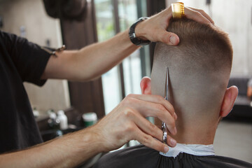 Close up rear view shot of a hairstylist using scissors, cutting hair of male client