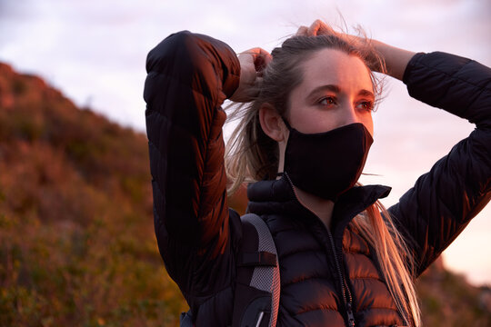 Young woman adjusting face mask on top of mountain