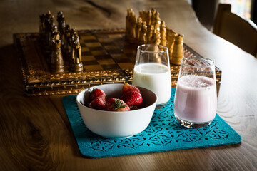 Glasses with milk and strawberry milkshake. Pink strawberry protein shake. Glasses on a wooden table and a blue napkin. Healthy nutrition during quarantine.