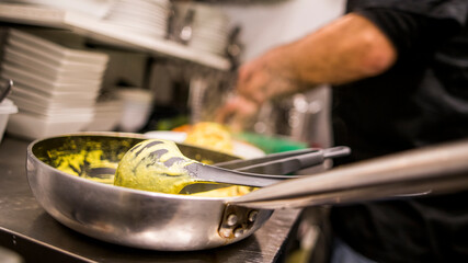 Primer plano de sartén en la que se ha elaborado una salsa de curry con el cocinero al fondo.