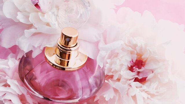 Pink perfume bottle with peony flowers, chic fragrance scent as luxury cosmetic, fashion and beauty product background, stock footage