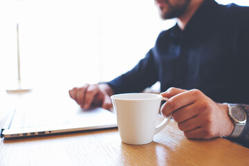 Brainstorming during planning strategy of start-up development using internet connection and computer laptop with cup of coffee sitting in office near copy space for your advertising messages