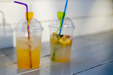 Selective focus. Two glasses of juice on a white wooden table. Cold drinks. Orange juice and mojito.