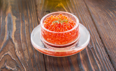 Red caviar in the glass jar on the wooden background