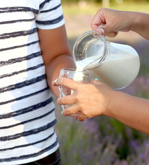 Milk is poured into a glass. Caucasian boy holds a glass with milk, mom pours milk from a glass...