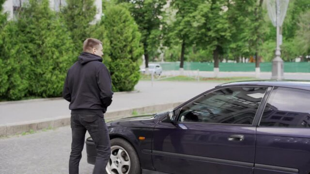 Car jacking thief steal car breaking door criminal job burglar Hijacks Auto thief black balaclava hoodie trying break into vehicle screwdriver Street crime violence gangster robber automobile parking