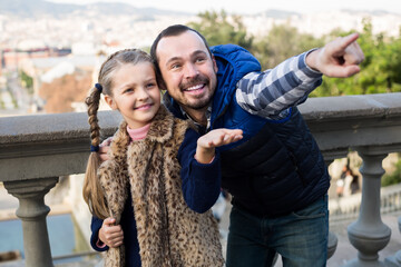 cheerful father and daughter pointing at sight during sightseeing tour outdoors