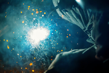 The welding process close-up. Flash of an electric arc and a lot of splashes of hot metal