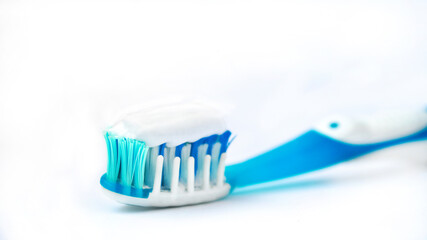 toothbrush on a white background close-up. white toothpaste on a blue toothbrush. the concept of clean teeth and oral cavity.
