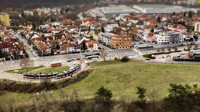 Aerial view of the tram stop and a crossroad near Divoka Sarka park in Prague. Active traffic on the road, cars, busses, and trams.People walking dogs in the park.