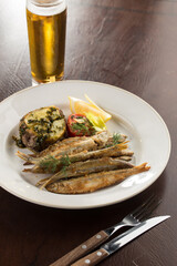 Seafood deep fried fish served with baked potato and beer on wooden table