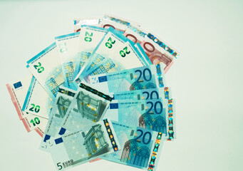 Five, ten and twenty euro banknotes are scattered on a white background