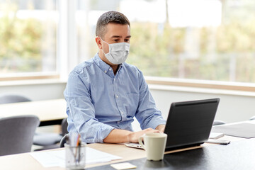 quarantine, remote job and pandemic concept - middle-aged man wearing face protective medical mask for protection from virus disease with laptop computer working at home office