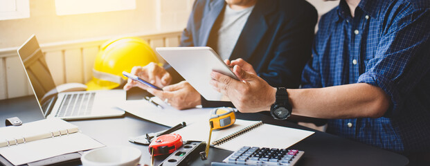 Modern engineers confer with colleagues and plan projects on the office desk.