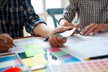 Professional web designers work together to design and draw mobile application layouts.