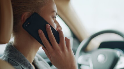 Back view of woman using phone behind steering wheel. Girl calling smartphone
