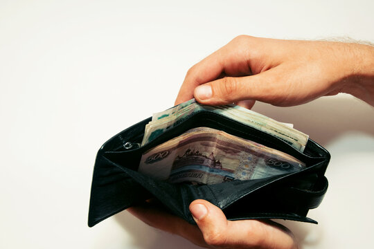 man holds a wallet with different face value of banknotes open