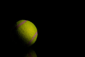 Bright Yellow Tennis Ball on dark mirror with reflections