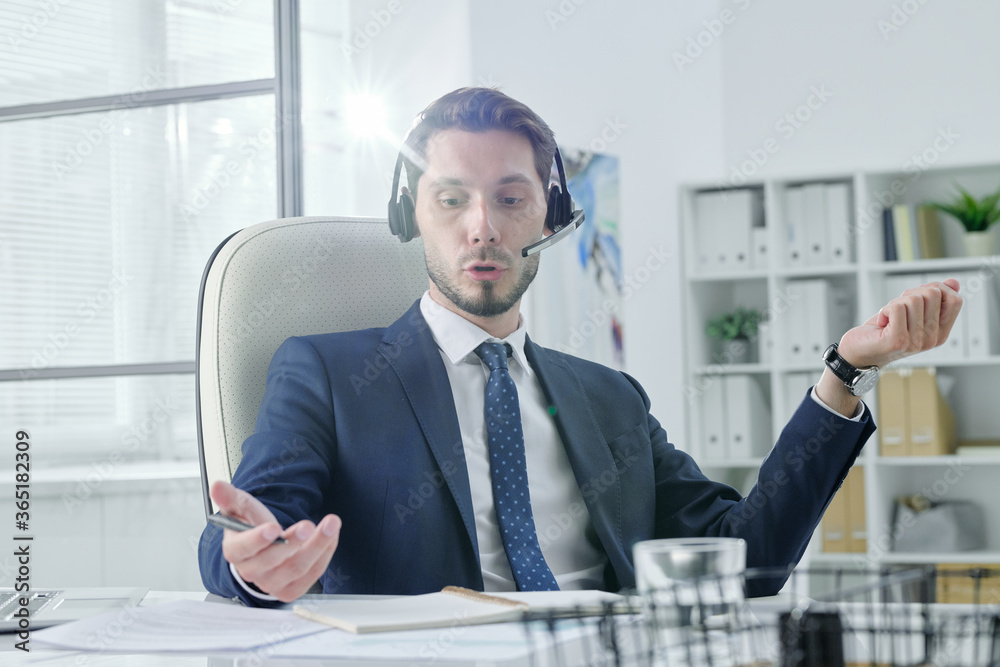 Poster young service support operator talking to customer using hands-free device in modern office