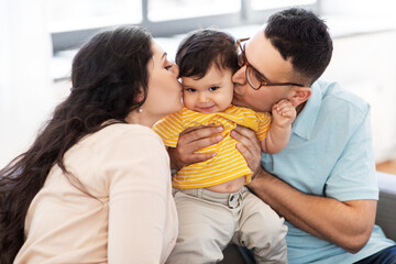 family and people concept - happy mother and father kissing baby son at home