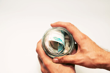 male hands hold a glass jar filled with paper money