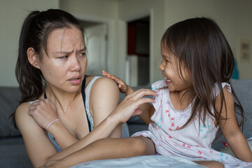 Afraid mother hurt by naughty toddler daughter with bad behavior. Misbehaving child and hurt female parent.