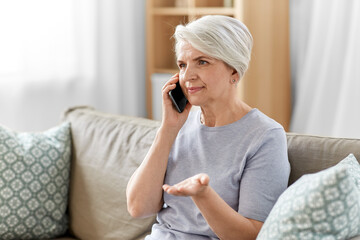 technology, communication and people concept - happy smiling senior woman calling on smartphone at...