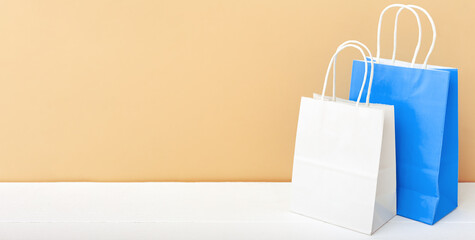 White blue craft paper bags. Shopping Mockup bags paper packages on white table beige light background with copy space. Shopping, sale, Food delivery service. Long web banner copy space
