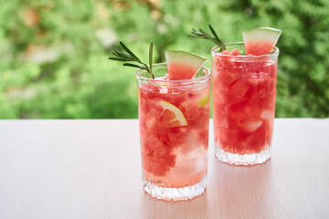 Summer refreshing drink with ice, slices of watermelon, lemon, rosemary,