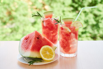 Summer refreshing drink with ice, slices of watermelon, lemon, rosemary,