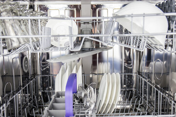 Stacked plates in dishwasher to be cleansed of stains with hot water, soap and detergent for shiny...