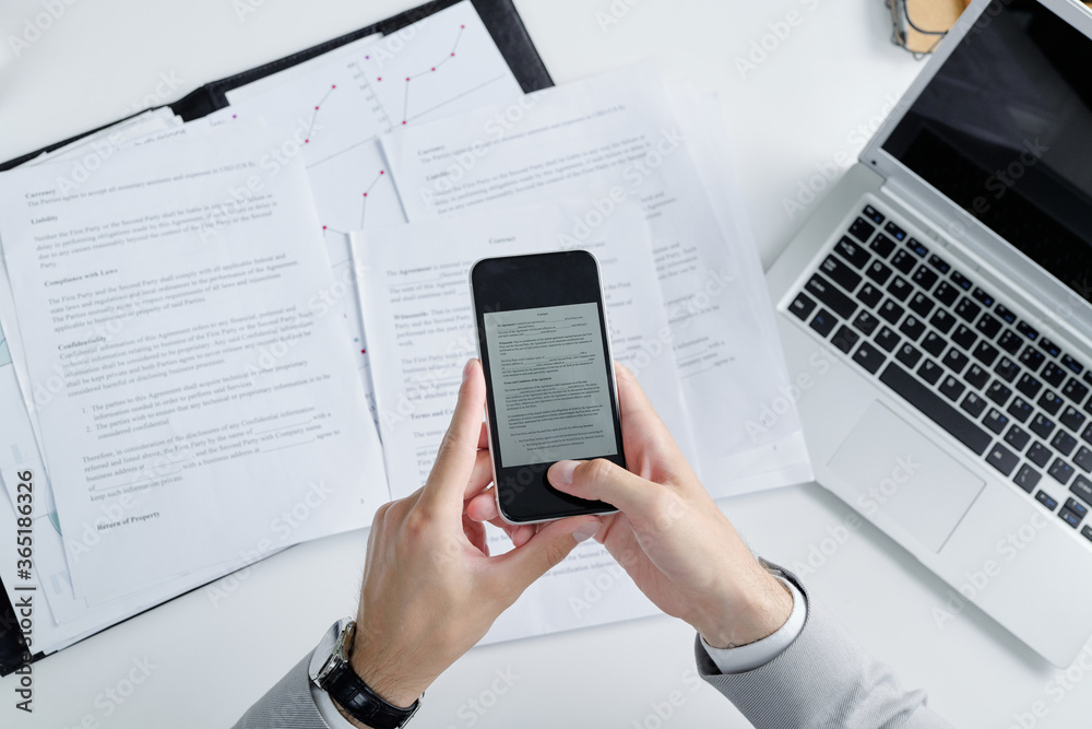 Poster Above view of unrecognizable lawyer using smartphone while photographing contract papers on table