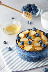 Blue Bowl of mini pancake cereal with blueberries, maple syrup and milk on concrete background. Tiny pancakes, new food trend concept. Cute healthy breakfast or snack. Recipe, menu.