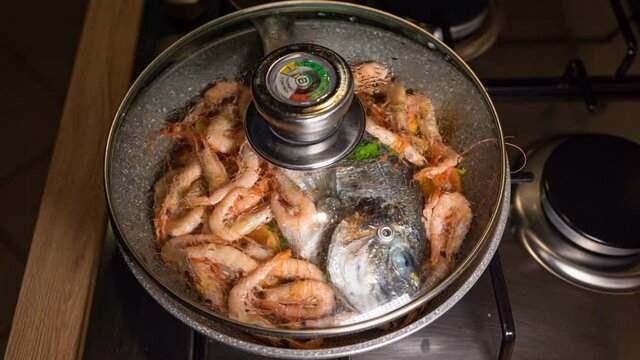 Naples, Italy. Timelapse of Sea Bream with Shrimp cooked in a pan with lid.  Fish cooking in a pan. Fish cooking on home stove.
