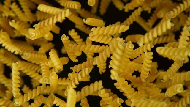 Super slow motion of flying uncooked italian pasta torti on black background. Filmed on high speed cinema camera, 1000 fps.