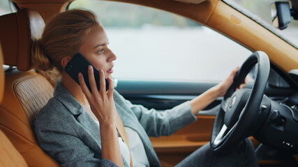 Fototapeta na wymiar Business woman talking phone behind steering wheel. Female executive using phone