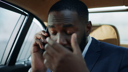 Worried african american man getting bad news on mobile phone at modern car.