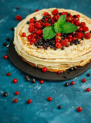 Pancakes with berries decorated with mint. Breakfast. Sweet homemade stack of pancakes
