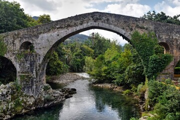View of an ancient bridge with a hanging Christian cross.
